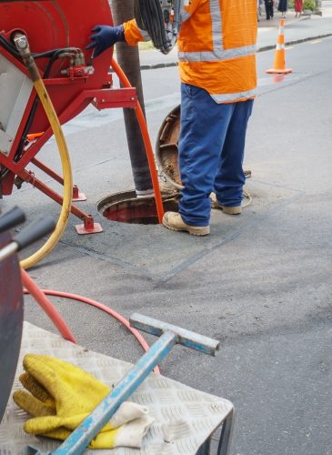 Worker,Unblocking,Sewers,Through,A,Manhole,On,Street.,Auckland.